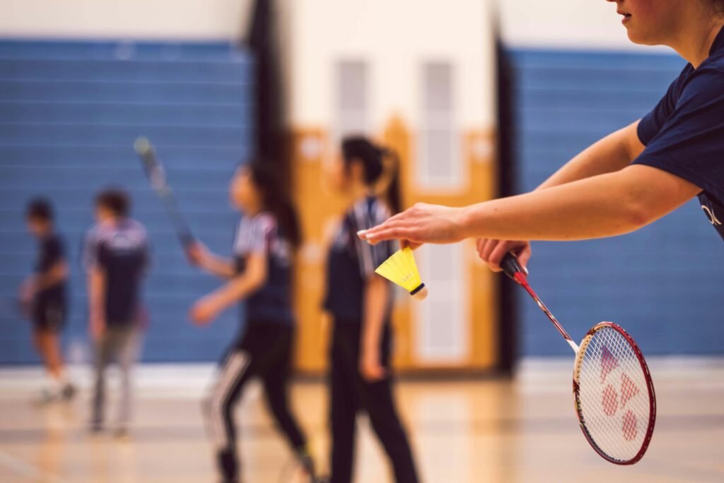 A group of young people enjoying a fun game of badminton indoors.