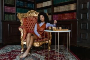 Elegant woman in a vintage armchair playing chess in a classic library. A moment of strategy and reflection.